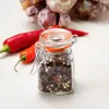 A small glass jar filled with peppercorns, with red chili peppers and garlic bulbs in the background. Anteprima dell’immagine prodotto
