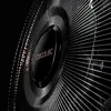 A close-up, angled view of the front grille of a black and copper fan, with the brand logo visible in the center. Podgląd zdjęcia produktu
