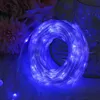 A coiled string of blue LED lights is shown in close-up, with soft pink flowers in the background. Produktbild-Vorschau