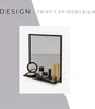 A black bathroom mirror with a shelf displaying various makeup items. Produktbild-Vorschau