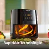A Philips Airfryer is shown on a table with some food items and greenery around it. The airfryer has a digital display showing '180' and animated arrows inside to illustrate the 'RapidAir Technologie'. Produktbild-Vorschau