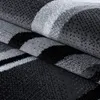 A close-up, folded view of a carpet with abstract wave patterns in shades of gray, black, and white. Anteprima dell’immagine prodotto