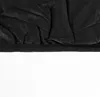 A close-up view of the bottom hem of a black quilted jacket. Voir les images du produit