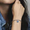 A woman's wrist wearing a silver bracelet with a blue butterfly charm. Podgląd zdjęcia produktu