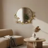 A round mirror with a decorative frame is mounted on a wall above a sofa and a coffee table in a living room setting. Voir les images du produit