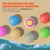 Several colorful beach umbrellas are arranged on a sandy beach with waves in the foreground. Produktbild-Vorschau