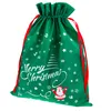 A green Christmas gift bag with red drawstrings, decorated with white snowflakes, stars, a Christmas tree, Santa Claus, and the text "Merry Christmas". Produktbild-Vorschau