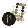 A sheet of round stickers with numbers from 1 to 24, in black, gold, gray, and white, is shown next to a single black sticker with the number 11 in gold. Produktbild-Vorschau