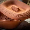 A close-up shot of a terracotta pot with a lid, showing decorative patterns. Voir les images du produit