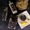 A collection of bath and body products arranged on a dark, textured surface. Produktbild-Vorschau