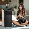 A woman is sitting on the floor next to a portable air conditioner, using her smartphone. There are WiFi symbols overlaid on the image. Produktbild-Vorschau