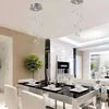 A modern dining room with a glass-top table and chairs, illuminated by two spiral crystal chandeliers. Produktbild-Vorschau
