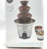 A chocolate fountain on a white background, with some strawberries and biscuits in bowls next to it. Podgląd zdjęcia produktu
