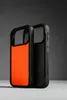 Two black iPhone cases are displayed side-by-side against a dark gray background. The case on the left has a bright orange interior, while the case on the right is entirely black. Podgląd zdjęcia produktu