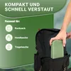 A hand is placing a green foldable cushion into the side pocket of a black backpack. The background has text and icons indicating compatibility with backpacks, handbags, and tote bags. Produktbild-Vorschau