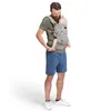 A man is carrying a baby in a grey baby carrier with a pattern of penguins on it. He is wearing a green t-shirt and blue shorts. Náhled obrázku produktu