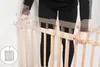 A person is installing a wooden baby gate against a wall. Produktbild-Vorschau