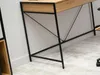 Close-up of the legs and underside of a desk with a wooden top and black metal frame. Náhled obrázku produktu