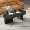 A modern living room scene with a black oval coffee table in the foreground, a tan sofa in the background, and a textured rug. Voir les images du produit