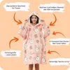 A woman wearing a pink hoodie blanket with a rabbit pattern, surrounded by marketing text and arrows. Produktbild-Vorschau