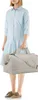 A person stands holding a duffel bag. Voir les images du produit