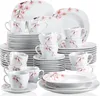 A collection of white porcelain dinnerware with a pink cherry blossom design, stacked and arranged for display. Voir les images du produit
