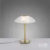A table lamp with a white, translucent shade and a gold-colored base and stem, placed on a white surface against a gray background. Voir les images du produit