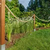 A garden scene with a rope fence and lush greenery. Produktbild-Vorschau