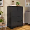 A black chest of drawers is shown in a room with a couch and a plant. Podgląd zdjęcia produktu