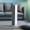 A white tower heater is placed on a gray rug in front of a gray sofa in a living room. Voir les images du produit