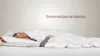 A woman is lying in bed, covered by a white duvet. Produktbild-Vorschau