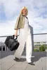 A woman walks with a bag in an urban outdoor setting. Anteprima dell’immagine prodotto