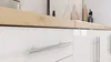 A close-up view of a modern kitchen cabinet with a wooden countertop. Produktbild-Vorschau