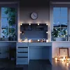 A vanity table with LED lights and makeup items, set in a room at night with a view of snowy mountains through the window. Anteprima dell’immagine prodotto