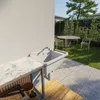 An outdoor sink and countertop setup next to a wall, with a garden and patio furniture in the background. Náhled obrázku produktu