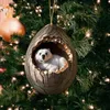 A Christmas ornament shaped like a cracked egg with a polar bear cub inside, hanging on a decorated Christmas tree. Produktbild-Vorschau