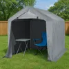 A grey tent-like structure with a blue camping chair and a small table inside, set up on a grassy lawn with a wooden fence in the background. Náhled obrázku produktu