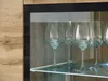 A close-up view of wine glasses inside a cabinet with a wooden exterior and a glass front. Voir les images du produit