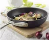 A frying pan with food being cooked in it, placed on a wooden board with onions and lettuce in the background. Produktbild-Vorschau