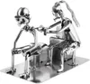 A metal sculpture of a tattoo artist tattooing a client, made from nuts, bolts, and other metal hardware. Podgląd zdjęcia produktu