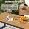 A close-up view of a wooden outdoor dining table with oranges and a magazine on it, set in a garden. Podgląd zdjęcia produktu
