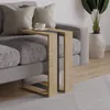 A modern C-shaped side table with a wood finish and dark accents is placed next to a grey sofa with two pillows. A cup of coffee sits on the table. A large potted plant is visible in the background. Anteprima dell’immagine prodotto