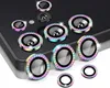 A collection of camera lens protectors with colorful, gem-like borders, arranged on a dark surface and a white surface. Produktbild-Vorschau