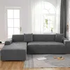 A sectional sofa covered in a gray, patterned slipcover is shown in a well-lit room. Produktbild-Vorschau