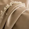 A close-up of a beaded hair accessory on a draped beige fabric. Anteprima dell’immagine prodotto