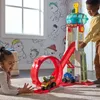 Two children playing with a Paw Patrol toy tower and race track in a room with Paw Patrol themed wallpaper. Náhľad obrázku produktu