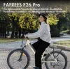 A woman is riding an electric bicycle on a paved path in an outdoor setting. Produktbild-Vorschau