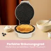 A waffle maker is shown open with a freshly made waffle inside, alongside a bowl of whipped cream and blueberries. Produktbild-Vorschau