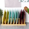 A bamboo dish rack holding several colorful plates. Produktbild-Vorschau