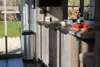 A kitchen counter with a trash can, wine bottle, glasses, and tomatoes. Produktbild-Vorschau